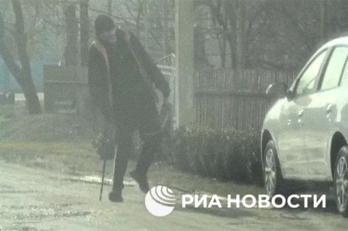 Скриншот опубликованного ФСБ видео, на котором человек с тростью кладет пакет под автомобиль